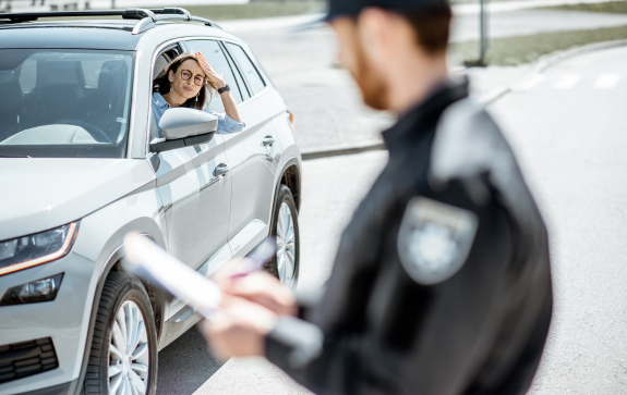 Condutora sendo abordada em blitz por policial de trânsito, simbolizando fiscalização veicular e controle de infrações nas vias urbanas.
